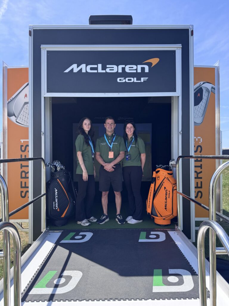 Dryvebox team welcoming visitors at the entrance ramp of the McLaren Golf branded mobile golf simulator